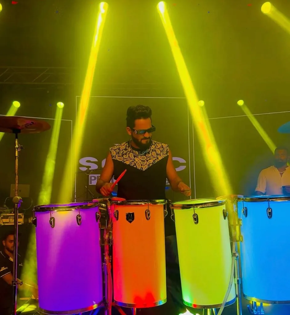 KKsonic playing colorful illuminated drums under yellow stage lights